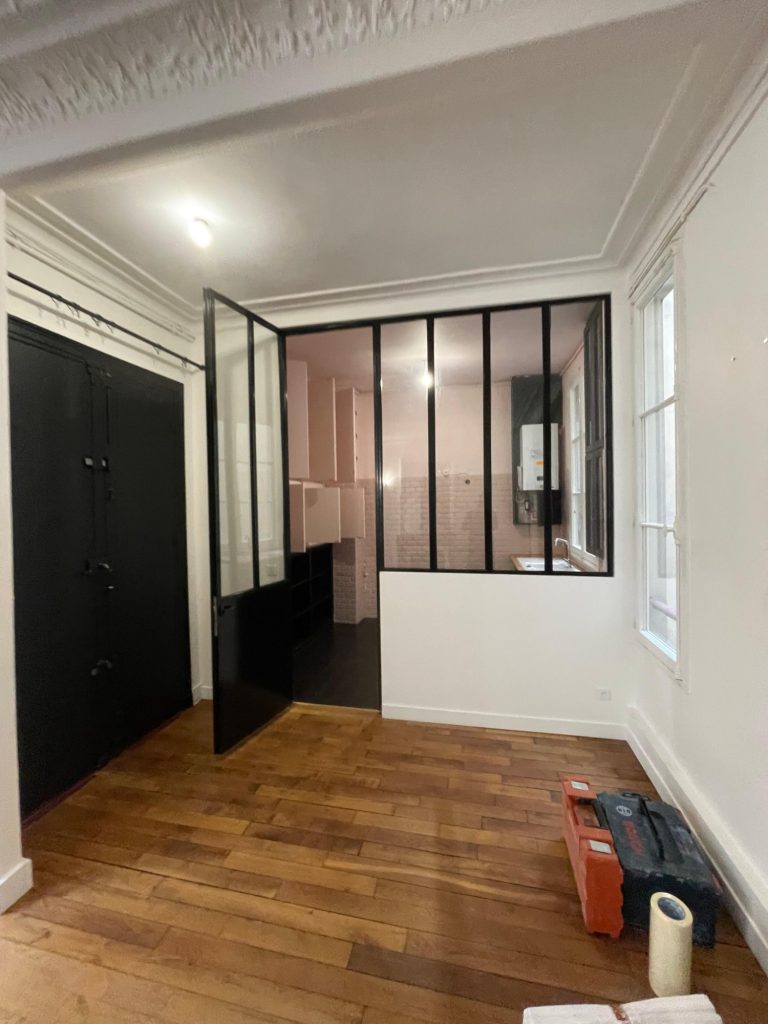 Intérieur moderne avec murs en verre, sol en bois et mur noir.